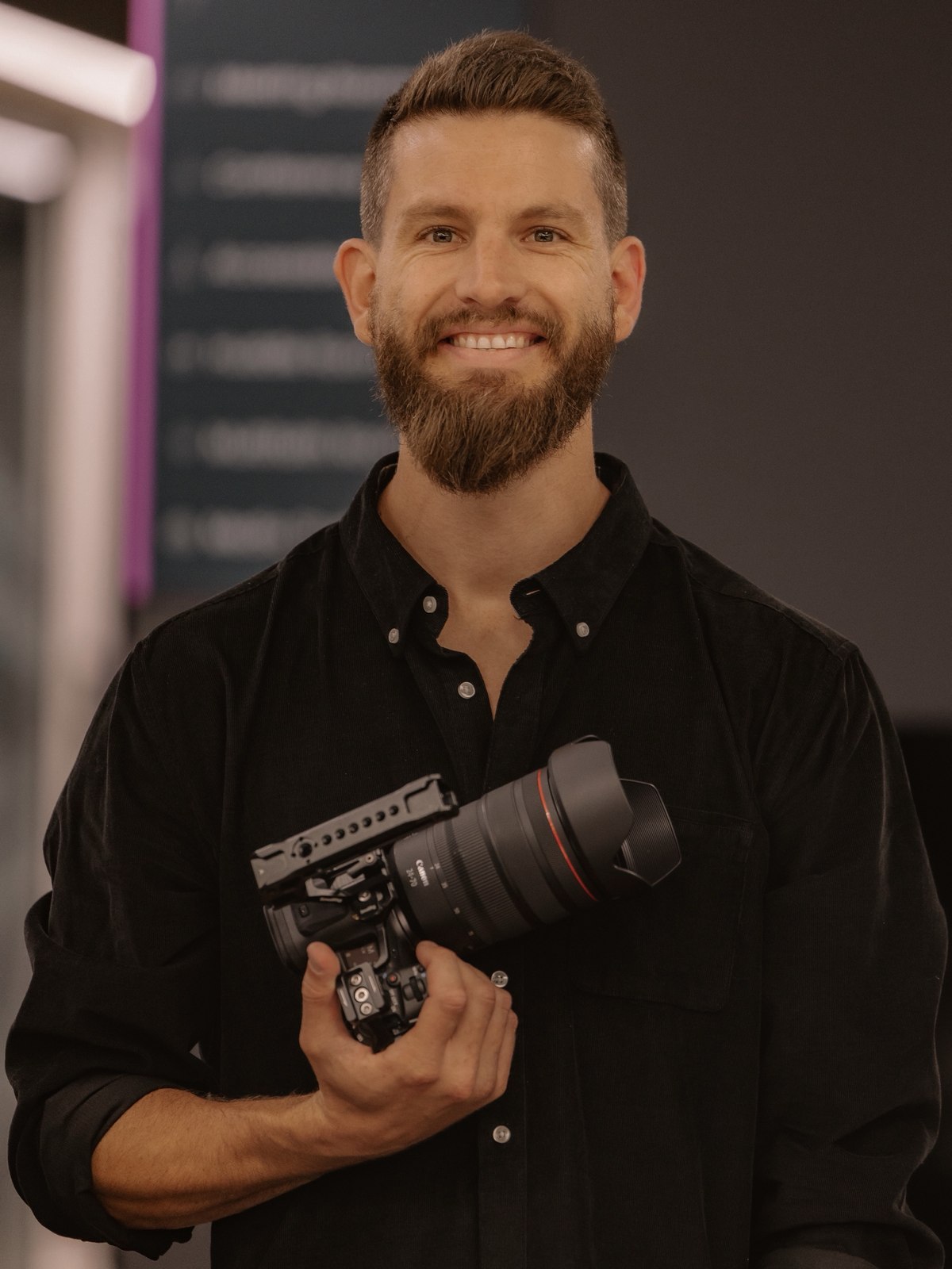 Portrait of Tim smiling, holding a Canon camera